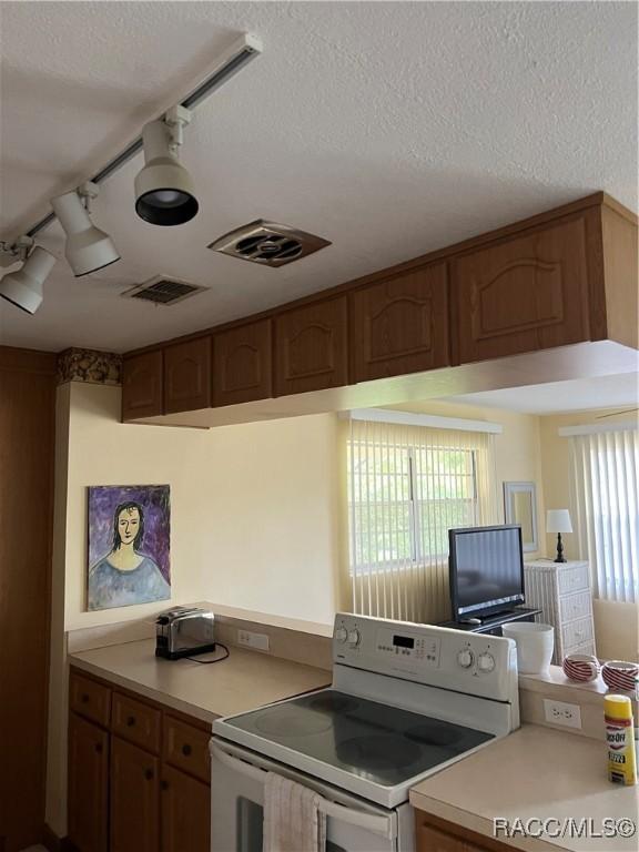 13 N Wadsworth Ave, Beverly Hills, FL 34465 - kitchen featuring white electric range oven, light countertops, a textured ceiling, and brown cabinets