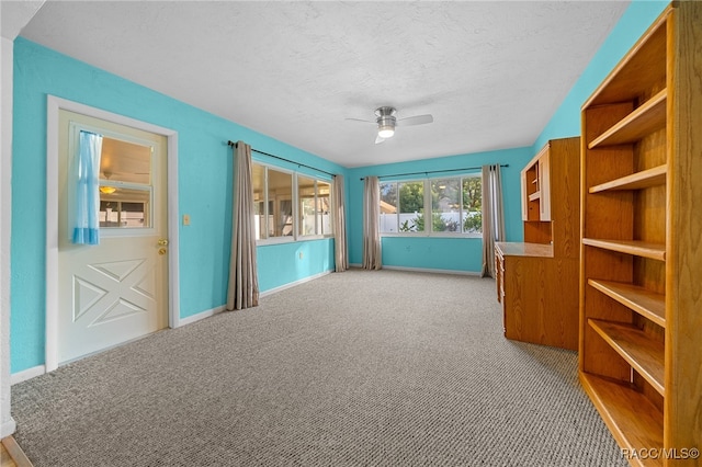 carpeted spare room with a textured ceiling and ceiling fan