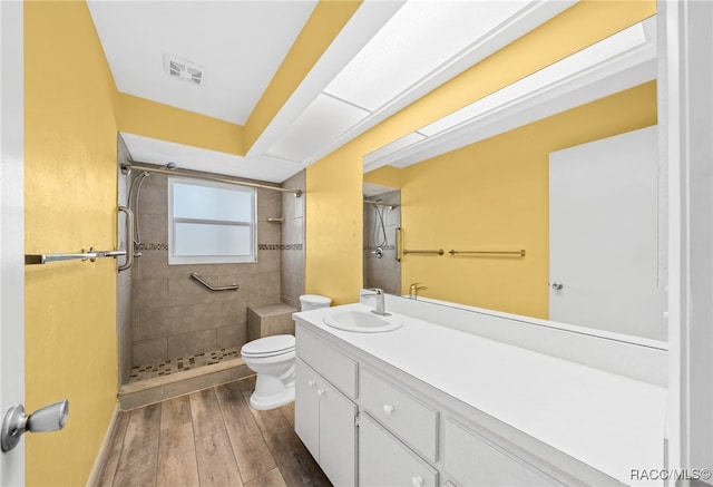 bathroom with toilet, vanity, and a tile shower