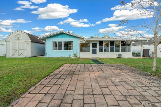 rear view of house with a storage shed, a patio area, a sunroom, and a yard