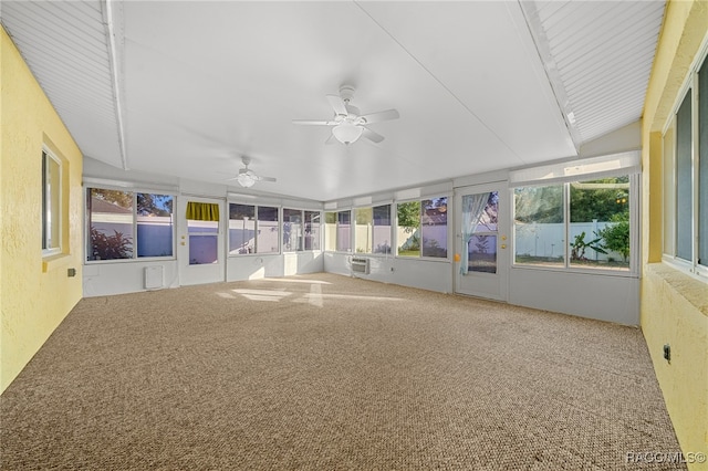 unfurnished sunroom featuring vaulted ceiling, ceiling fan, plenty of natural light, and an AC wall unit