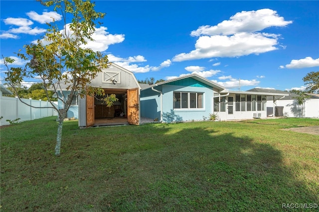 view of front of house featuring a front yard, a sunroom, and a storage shed