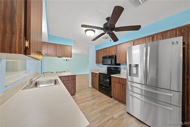 kitchen with kitchen peninsula, ceiling fan, light wood-type flooring, black appliances, and sink