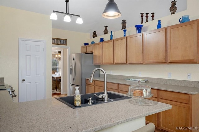 kitchen with sink, stainless steel fridge, light stone countertops, decorative light fixtures, and a kitchen bar