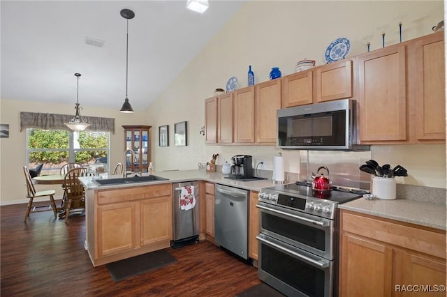 kitchen with dark wood-type flooring, sink, hanging light fixtures, kitchen peninsula, and stainless steel appliances