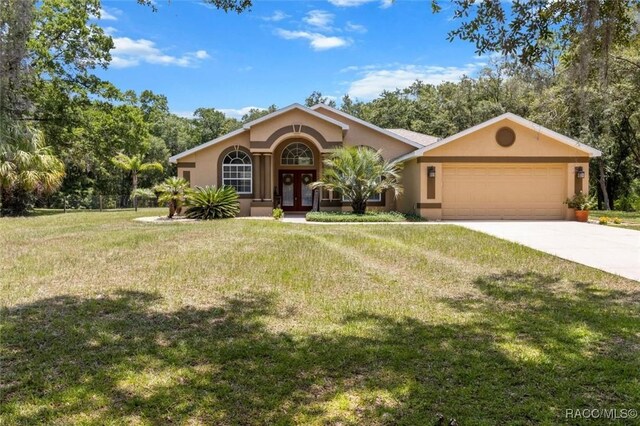 8583 N Tibet Ter, Dunnellon, FL 34433 - view of front of property with french doors, stucco siding, a garage, a front yard, and driveway