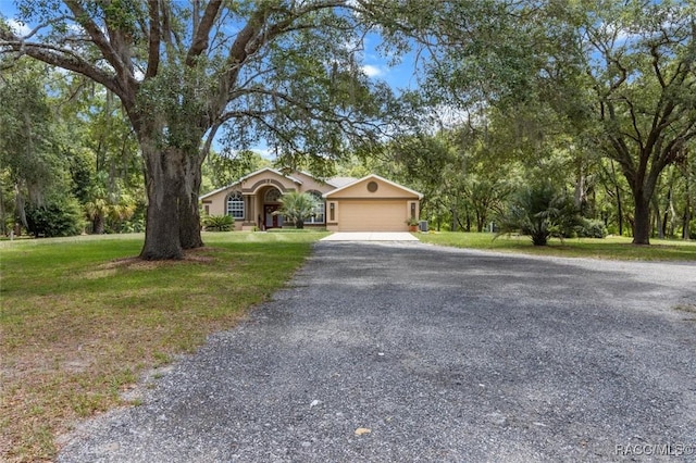 8583 N Tibet Ter, Dunnellon, FL 34433 - view of front of home with gravel driveway, a garage, a front lawn, and stucco siding