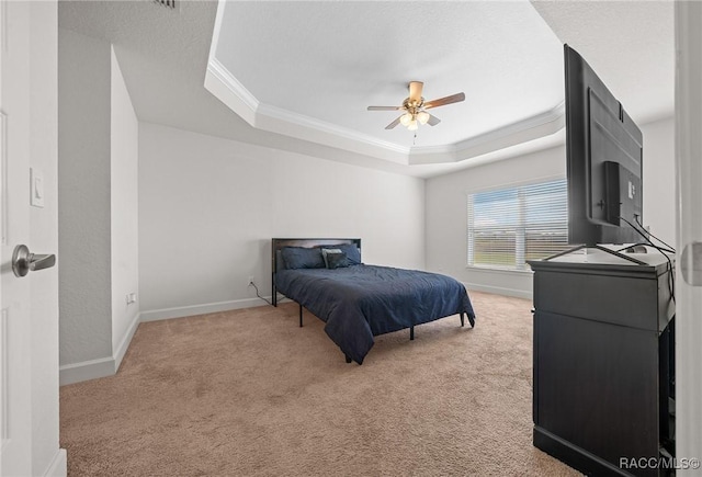 carpeted bedroom with ceiling fan, ornamental molding, and a tray ceiling