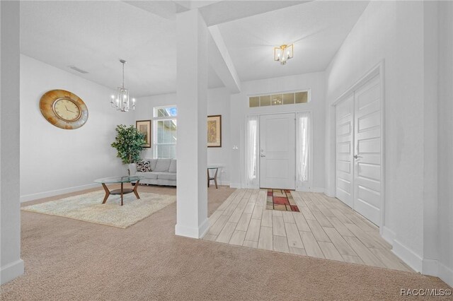 foyer entrance with light carpet and an inviting chandelier