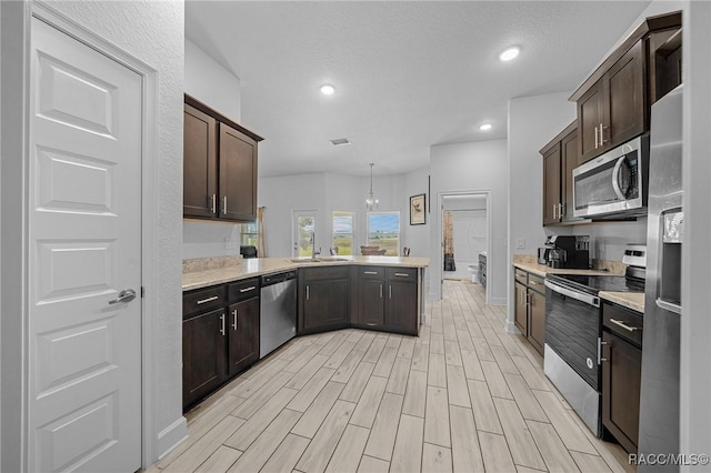 kitchen with decorative light fixtures, kitchen peninsula, stainless steel appliances, and dark brown cabinetry