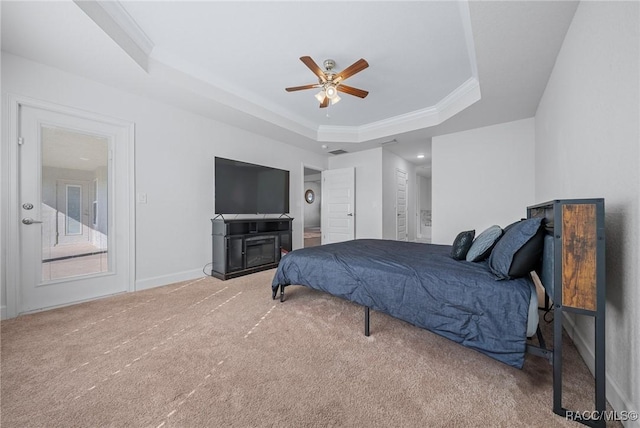 carpeted bedroom with ceiling fan, crown molding, and a tray ceiling