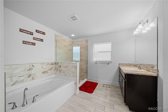 bathroom with a textured ceiling, vanity, and independent shower and bath