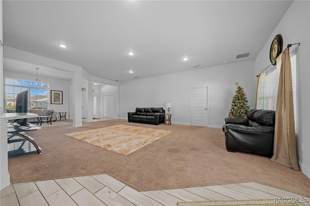 living room featuring light colored carpet, a wealth of natural light, and an inviting chandelier