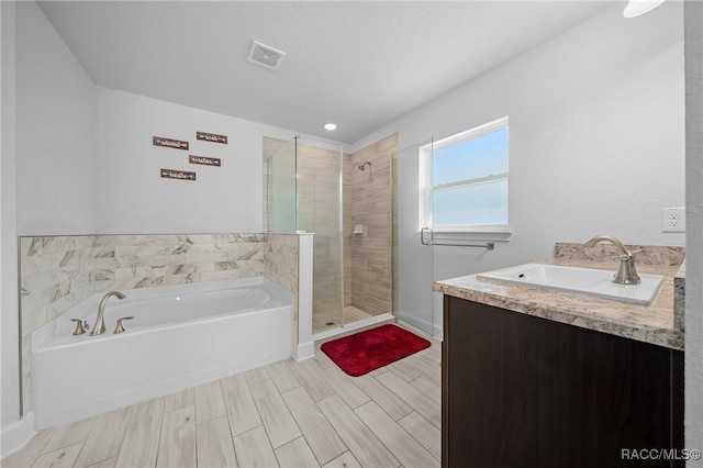 bathroom with vanity and shower with separate bathtub