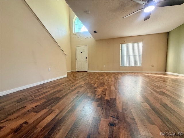 unfurnished living room with a textured ceiling, ceiling fan, a high ceiling, and dark hardwood / wood-style floors