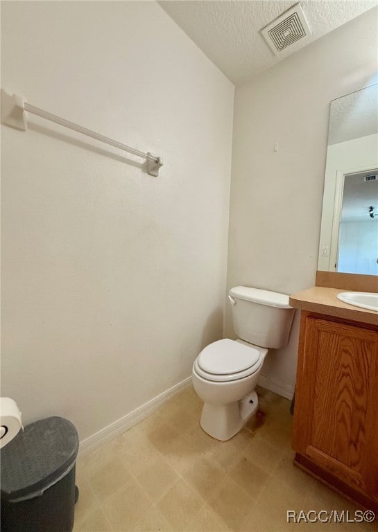 bathroom with vanity, a textured ceiling, and toilet