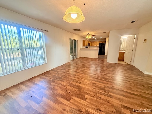 unfurnished living room with ceiling fan, light wood-type flooring, and a textured ceiling