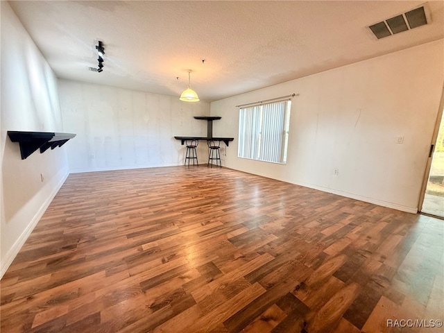 unfurnished living room featuring a textured ceiling and dark hardwood / wood-style flooring