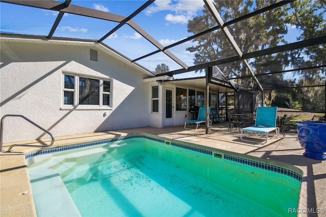 view of pool featuring glass enclosure, ceiling fan, and a patio