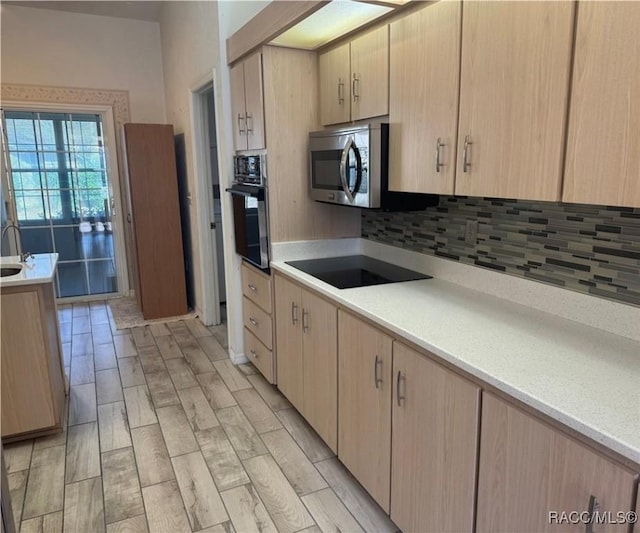 kitchen featuring tasteful backsplash, light brown cabinetry, and black appliances