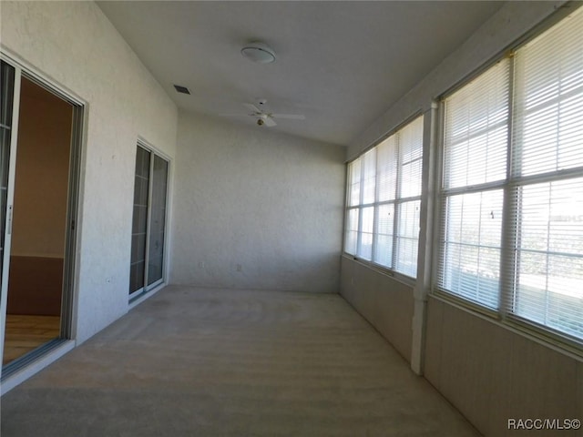 unfurnished sunroom with ceiling fan