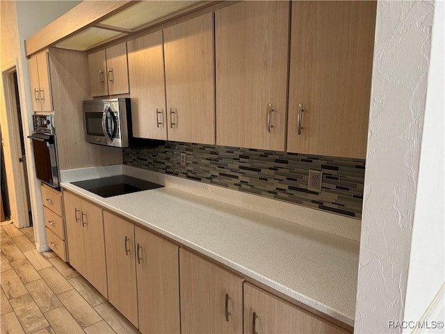 kitchen with black appliances, light hardwood / wood-style floors, backsplash, and light brown cabinetry