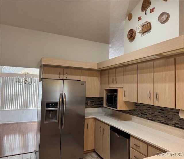 kitchen with appliances with stainless steel finishes, light brown cabinets, a chandelier, and decorative backsplash