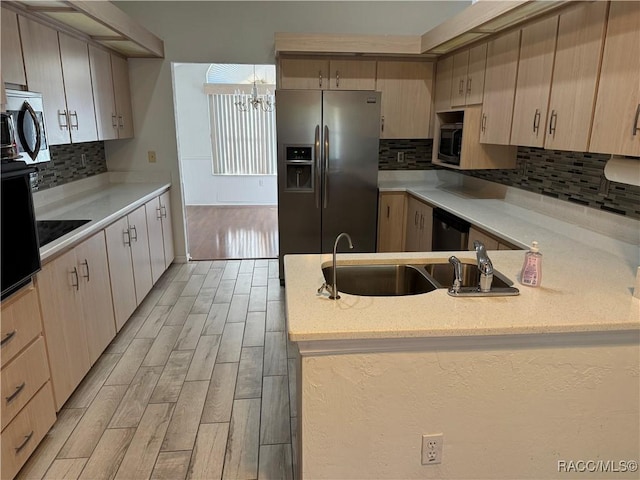 kitchen featuring kitchen peninsula, backsplash, stainless steel appliances, and a chandelier