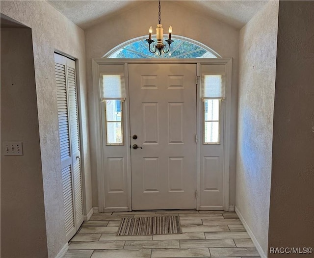 foyer entrance with an inviting chandelier and vaulted ceiling