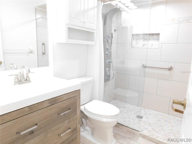 bathroom featuring vanity, a tile shower, and toilet