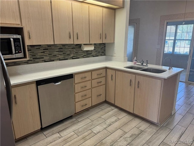 kitchen featuring light brown cabinetry, sink, kitchen peninsula, and appliances with stainless steel finishes