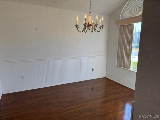 empty room with dark wood-type flooring, vaulted ceiling, and a notable chandelier