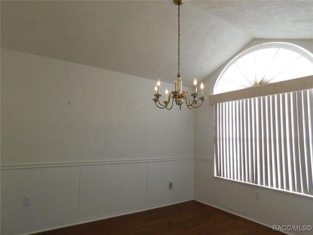 unfurnished room featuring dark hardwood / wood-style flooring, vaulted ceiling, and a notable chandelier