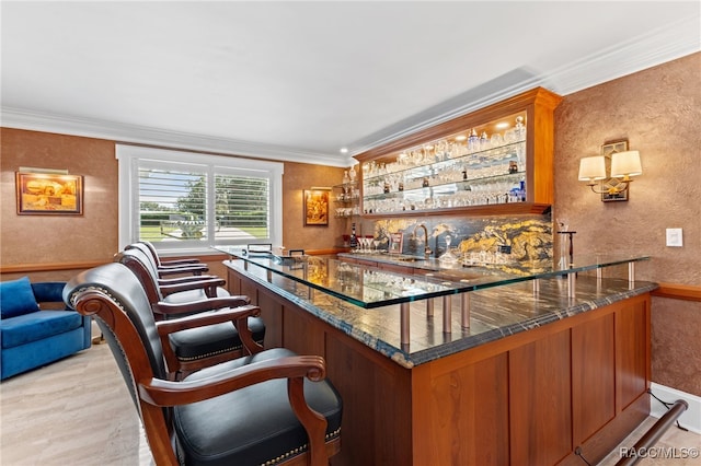 bar with ornamental molding, sink, and dark stone counters