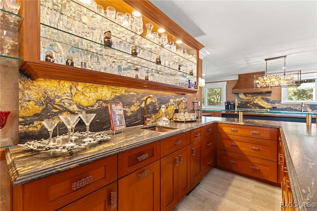 bar featuring decorative backsplash, sink, pendant lighting, light tile patterned floors, and dark stone countertops