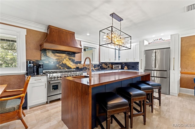 kitchen with white cabinetry, a center island with sink, stainless steel appliances, and custom range hood