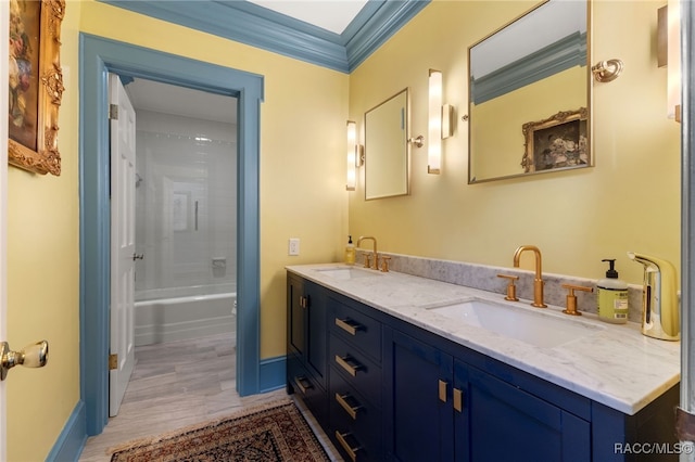 bathroom with crown molding, vanity, wood-type flooring, and washtub / shower combination