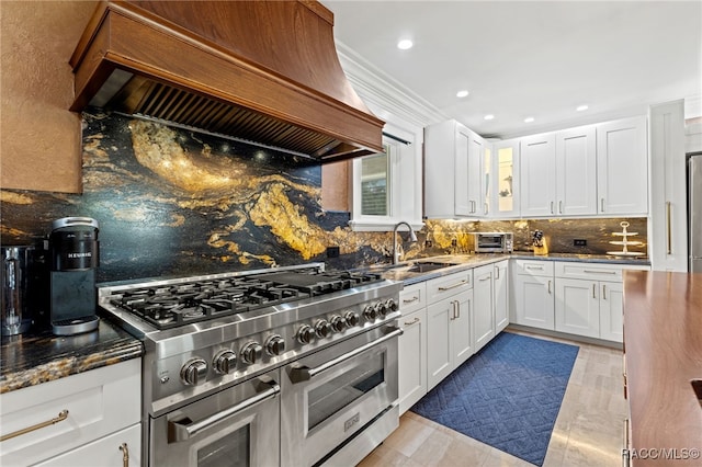 kitchen with premium range hood, dark stone countertops, double oven range, decorative backsplash, and white cabinets