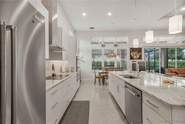 kitchen featuring appliances with stainless steel finishes, pendant lighting, white cabinetry, an island with sink, and sink