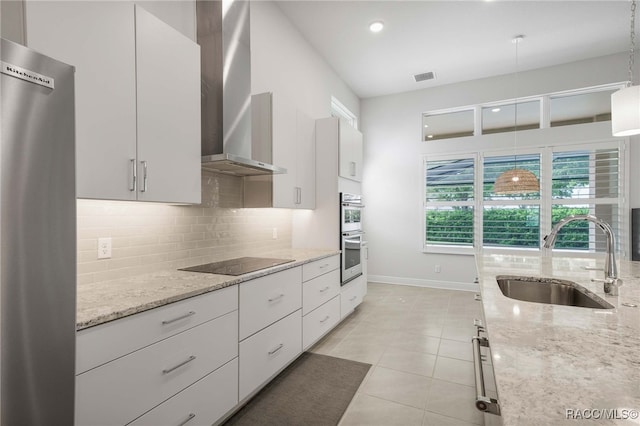 kitchen featuring visible vents, a sink, black electric stovetop, wall chimney range hood, and backsplash