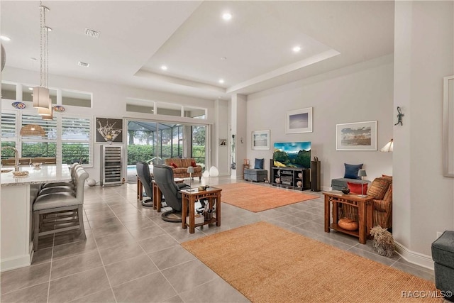 living room featuring a high ceiling, light tile patterned floors, wine cooler, and a tray ceiling