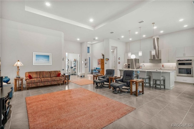 tiled living room featuring a towering ceiling and a tray ceiling