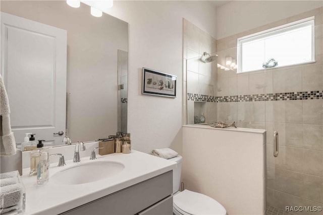 bathroom featuring vanity, a shower with shower door, and toilet