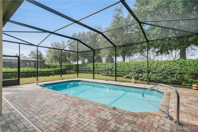 view of swimming pool featuring a patio, a yard, and glass enclosure