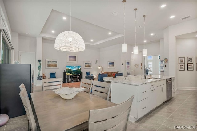 dining area featuring light tile patterned flooring, sink, and a tray ceiling