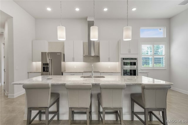 kitchen featuring white cabinets, visible vents, tasteful backsplash, appliances with stainless steel finishes, and an island with sink