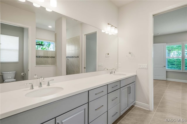 bathroom with baseboards, double vanity, a sink, and tile patterned flooring