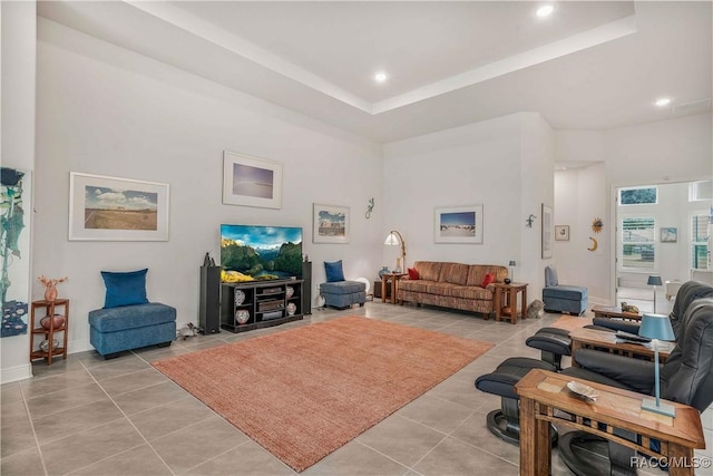 living room featuring light tile patterned flooring, a towering ceiling, and a tray ceiling