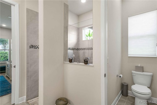 bathroom with tile patterned flooring, tiled shower, and toilet