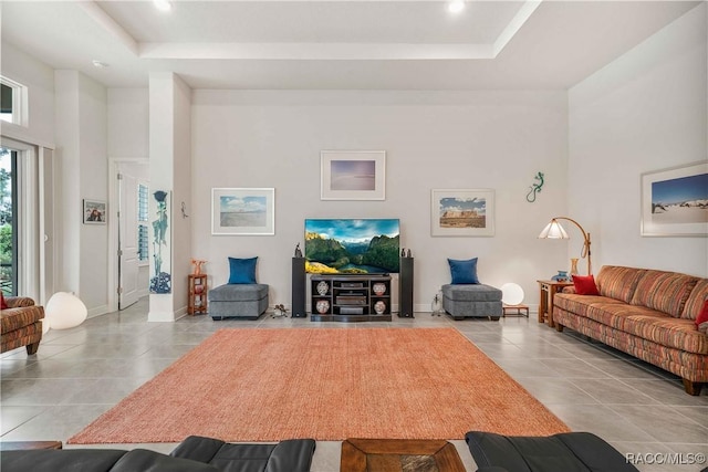 tiled living room featuring a raised ceiling and a high ceiling